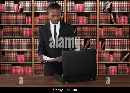 Avocat avec Papiers et Briefcase At Desk In Office Banque D'Images