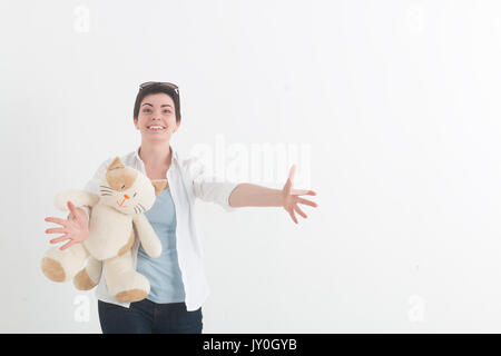 Jeune femme en blouse blanche avec cat se prépare à hug quelqu'un, en écartant ses mains bien à part et l'accueil souriant. Banque D'Images