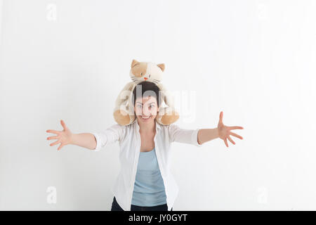 Succès des émotions positives. Happy young woman in white shirt étend les mains en avant, voulant hug quelqu'un. Chat peluche est assise sur son cou. Banque D'Images