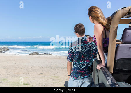 Couple leaning on voiture décapotable at beach Banque D'Images