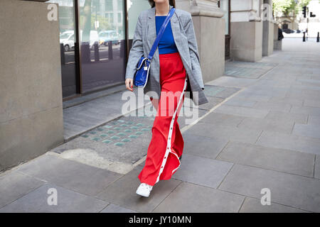 Walking Woman in red top, pantalon et veste gris bleu Banque D'Images