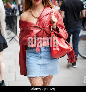 Mid section of woman in red cuir veste et jupe en denim Banque D'Images