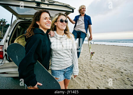 Caucasian friends près de voiture éclosent à beach holding skateboards Banque D'Images