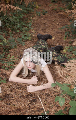 Adolescente blonde dans un endroit de la forêt portant des pantalons de camouflage et un t-shirt blanc Banque D'Images