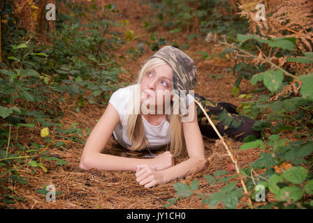 Adolescente blonde dans un endroit de la forêt portant des pantalons de camouflage et un t-shirt blanc Banque D'Images