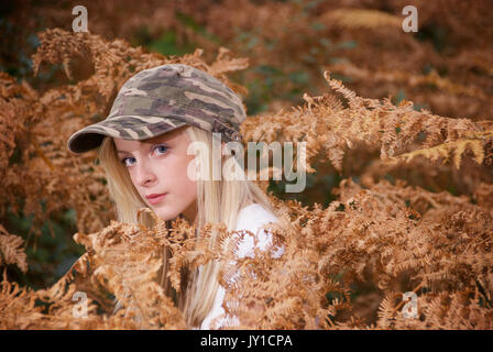 Adolescente blonde dans un endroit de la forêt portant des pantalons de camouflage et un t-shirt blanc Banque D'Images