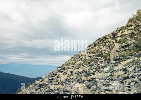Un touriste fait son chemin à travers les dépôts de pierre homme monter sur la colline de montagne Banque D'Images