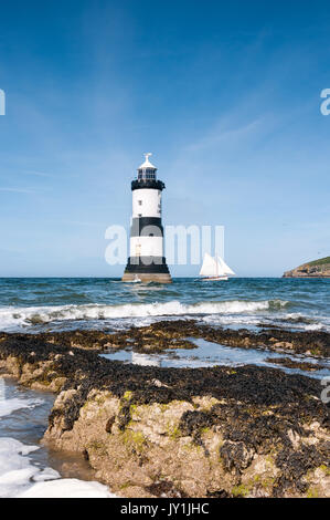 Penmon phare avec la voile en passant par, Anglesey, Pays de Galles, Royaume-Uni Banque D'Images