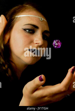 Une jeune femme habillée comme un elfe avec un polyèdre vingt faces souvent utilisé dans les jeux de rôles. Banque D'Images