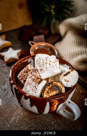 Nouvel An et Noël. Sucreries traditionnelles. Une tasse de chocolat chaud avec de la guimauve frits sur le feu, d'étoiles, avec d'épices sweater noir sur sto Banque D'Images