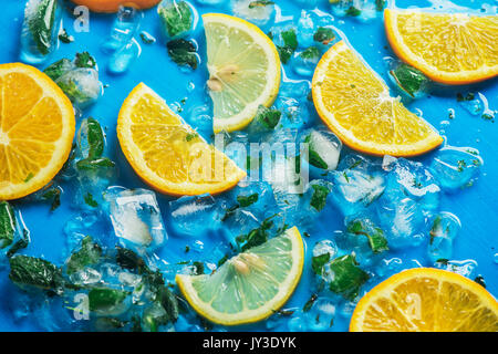 Close-up of sliced oranges et citrons sur un fond bleu avec des cubes de glace