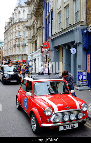 Un classique mini car avec l'un des célèbres taxis noirs de Londres derrière, dans Wardour Street, Soho, près de Chinatown, Londres Banque D'Images