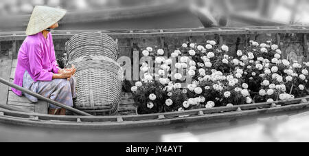 Farmer sitting sur le bateau la vente de fleurs à les clients d'acheter pour couvrir le coût du soutien à sa famille à Can Tho, Vietnam. Banque D'Images