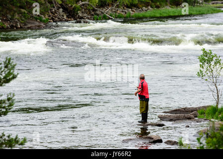 Byglandsfjord, Norvège - 1 août 2017 : Voyage de l'homme documentaire debout sur rock dans l'eau pendant la pêche. En arrière-plan d'eau vive. Banque D'Images