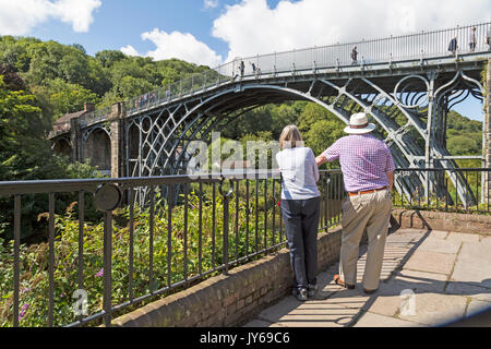 Deux personnes âgées touristes stand et admirer le célèbre pont de fer sur la rivière Severn, dans la ville de Liverpool, dans le Shropshire, en Angleterre. Banque D'Images