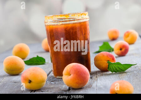 Confiture d'abricot en bocal de verre et fruits frais, sur fond de bois Banque D'Images