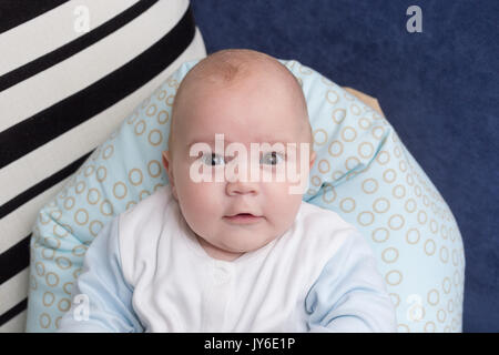 Portrait of a cute baby boy sitting sur un oreiller. Sept mois, Adorable enfant heureux. Banque D'Images