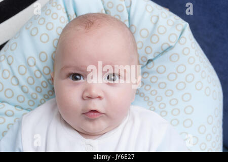 Portrait of a cute baby boy sitting sur un oreiller. Sept mois, Adorable enfant heureux. Banque D'Images