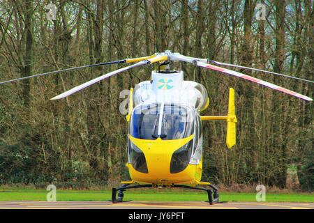 Hélicoptère Ambulance. Hélicoptère jaune sur le terrain en face de la forêt, England UK. Banque D'Images