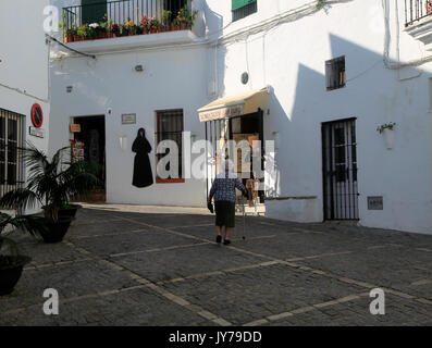 Femme marche dans la rue pavée, des bâtiments blanchis à Vejer de la Frontera, province de Cadiz, Espagne Banque D'Images