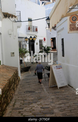 Femme marche dans la ruelle pavée bâtiments blanchis à la chaux de Vejer de la Frontera, province de Cadiz, Espagne Banque D'Images