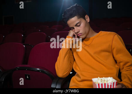 Bored man with popcorn dormir dans le théâtre Banque D'Images