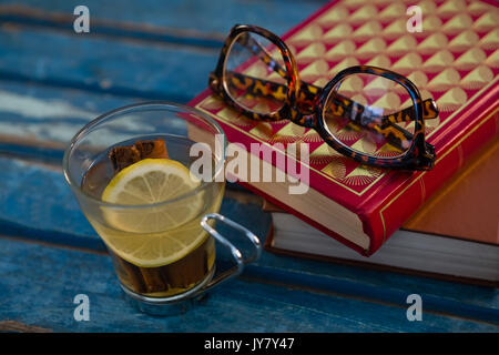 Close up of thé citron par les livres et les lunettes sur la table en bois Banque D'Images