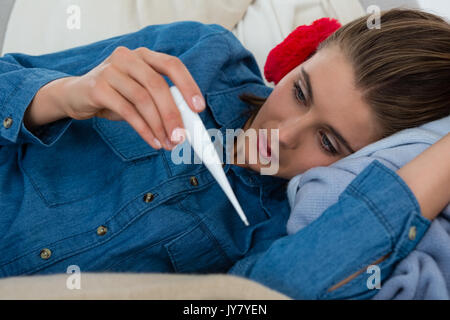 Thermomètre de contrôle femme couchée sur un canapé à la maison Banque D'Images