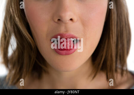 Mid section of woman eating framboise contre fond blanc Banque D'Images