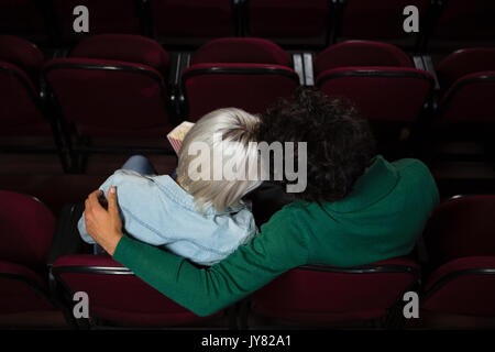 Vue arrière du couple having popcorn tout en regardant dans le théâtre de film Banque D'Images