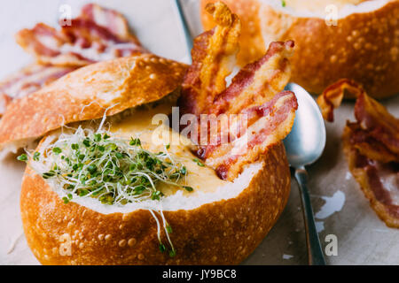 Soupe de crème dans bol de pain avec du bacon et pousses de broccoli Banque D'Images