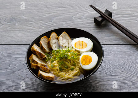 Soupe ramen japonais avec du poulet et un œuf dans un bol noir Banque D'Images