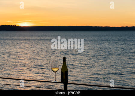 Seul avec une bouteille de vin en verre sur une terrasse en bord de rougeoyant au coucher du soleil Banque D'Images