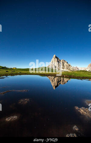 Le profil de la gusela se reflète dans une flaque à giau pass durant une nuit de pleine lune. Cortina d'ampezzo. dolomites. veneto italie. L'Europe. Banque D'Images