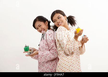 Deux malay woman holding pelita baju kedah sur le fond blanc Banque D'Images