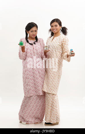 Deux malay woman holding pelita baju kedah sur le fond blanc Banque D'Images