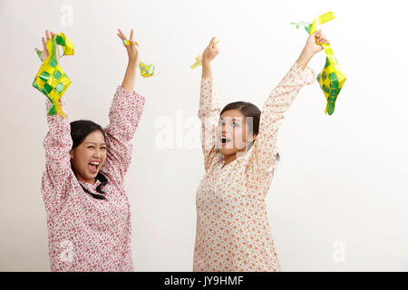 Deux malay woman holding ketupat baju kedah sur le fond blanc Banque D'Images