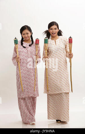 Deux malay woman holding pelita baju kedah sur le fond blanc Banque D'Images