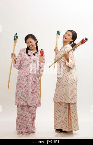 Deux malay woman holding pelita baju kedah sur le fond blanc Banque D'Images