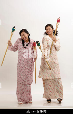 Deux malay woman holding pelita baju kedah sur le fond blanc Banque D'Images