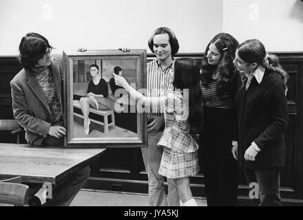 Deux élèves masculins et deux étudiantes portant une tenue habillée se sont réunis autour d'une jeune fille adolescente, tandis qu'elle montre les détails dans la peinture encadrée de ballerine assise, 1975. Banque D'Images