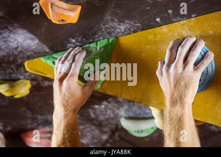 Gros plan du rock Climber's mains agrippant les poignées en indoor climbing gym Banque D'Images