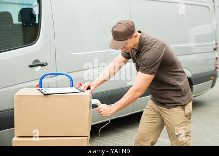 Jeune homme Livraison boîtes de carton et de numérisation du scanner de codes-barres Banque D'Images