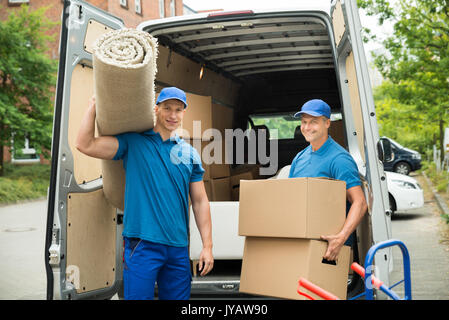 Deux hommes transportant des tapis et boîtes de carton en face de Van Banque D'Images