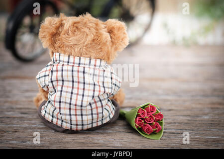 Ours en peluche tenant un bouquet de roses à valentine concept avec l'espace pour écrire, la sélection du point AF et flou, tonalité vintage photo. Banque D'Images