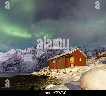 Le Nord s'allument des sommets enneigés et le chalet en bois par une nuit étoilée à Budalen Svolvaer Lofoten, Norvège Europe Banque D'Images