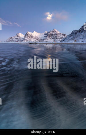 Pleine lune reflétée dans la mer de glace autour de la plage de Skagsanden surréaliste Flakstad Nordland County Iles Lofoten Norvège Europe Banque D'Images