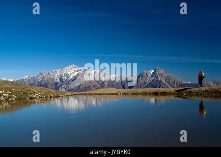 Un randonneur le long de la crête du mont San Primo reflétée dans un étang saisonnier. De là, la vue s'étend sur Grignetta et Grignone. Bellagio. Le lac de Côme. Banque D'Images