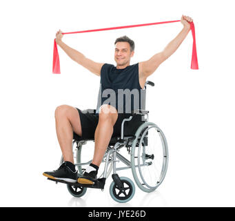 Homme handicapé en fauteuil roulant sur l'entraînement avec Resistance Band Over White Background Banque D'Images