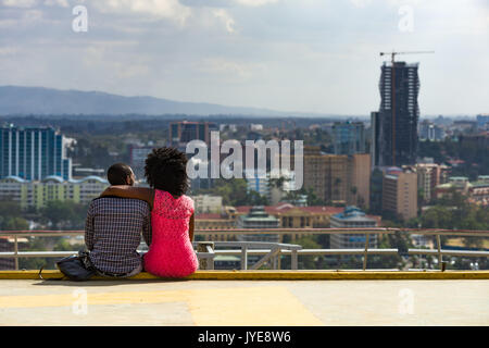 African couple assis en profitant de la vue du Kenyatta International Convention Centre Haut de toit au-dessus de la ville, Nairobi, Kenya Banque D'Images